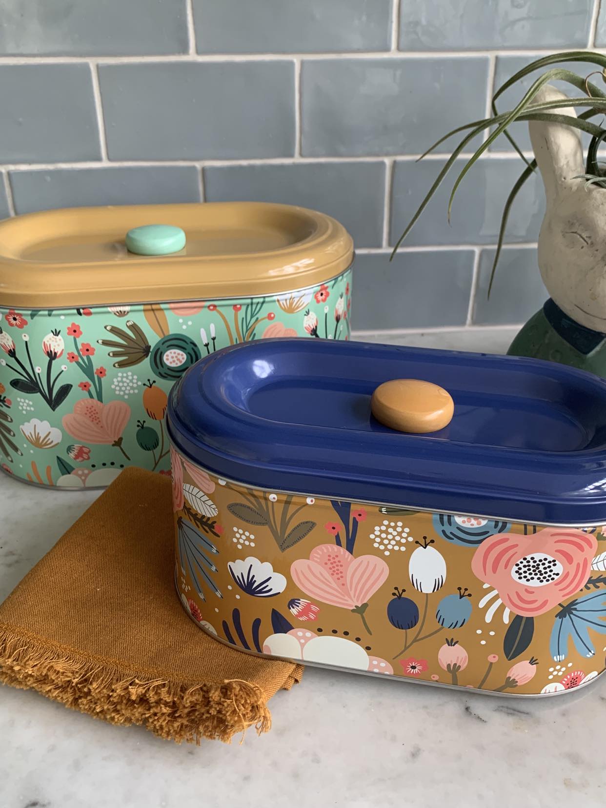 Two Spring Floral Storage Tins with LaVida designs on top of a counter.