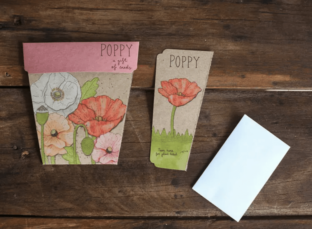 Sow n Sow Poppy seed packets and envelopes on a wooden table.