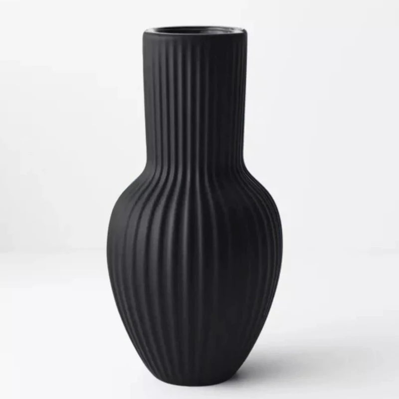 An Annix Tall Vase - Black by Floral Interiors on a white surface.