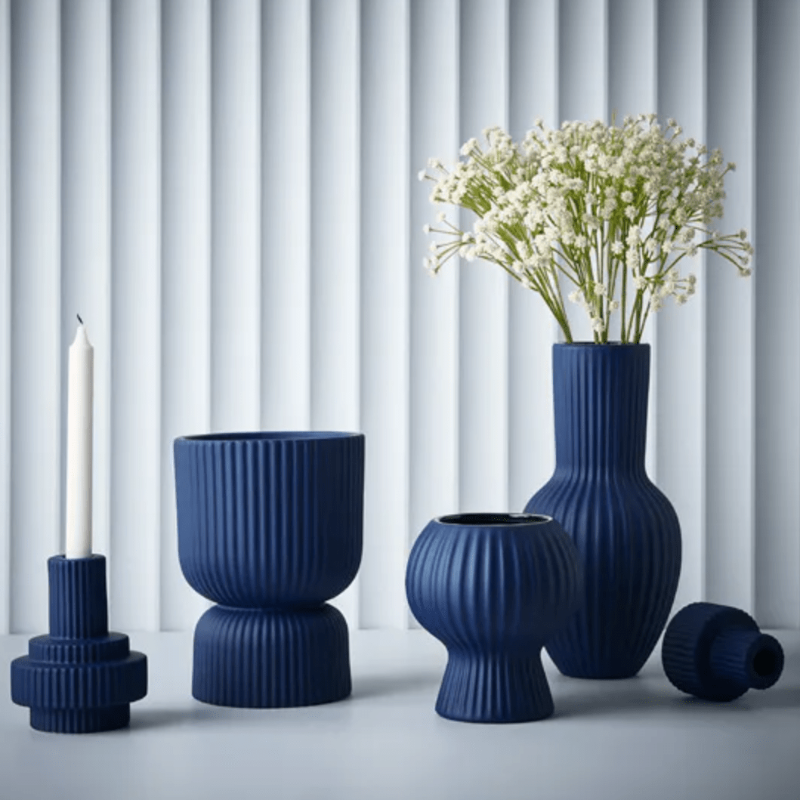 A group of Annix Tall Vase - Cobalt from Floral Interiors and a candle on a table.