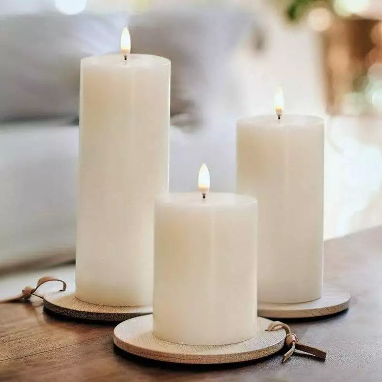 Three Enjoy Living Flameless Pillar Candles - 7.8cm x 20.3cm on a wooden table.