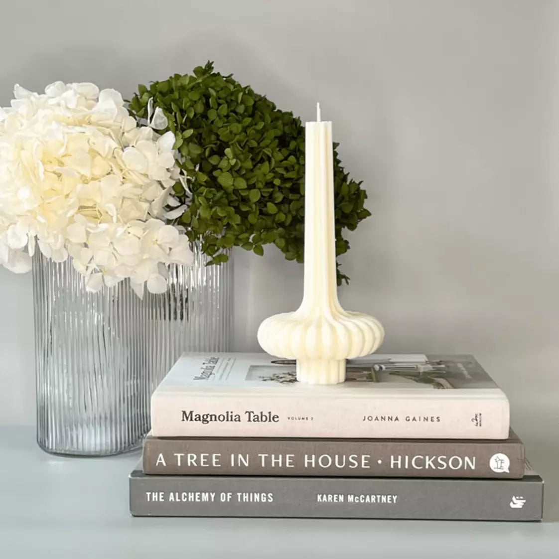 A Sculptural Soy Wax Candle - Sophia by Studio McKenna sits on top of a stack of books.