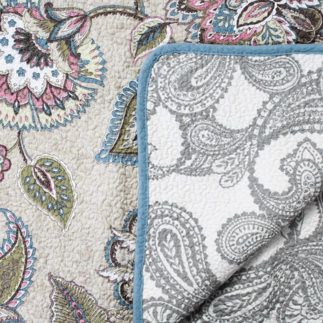 A LaVida Quilted Throw - Winter Flowers with a blue trim.