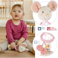 Thumbnail for A toddler in a pink shirt and beige pants sits holding the Pilbeam Fehn Rainmaker Mouse, a plush motor skills toy with glow-in-the-dark details, grasping ring, and rattle—a perfect sensory gift for baby showers.