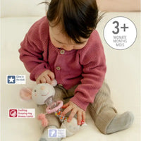 Thumbnail for A baby plays with the Pilbeam Fehn Rainmaker Mouse, wearing a pink sweater and beige pants on a light surface. This glowing sensory toy supports development—ideal for ages 3 months+ or as a thoughtful baby shower gift.