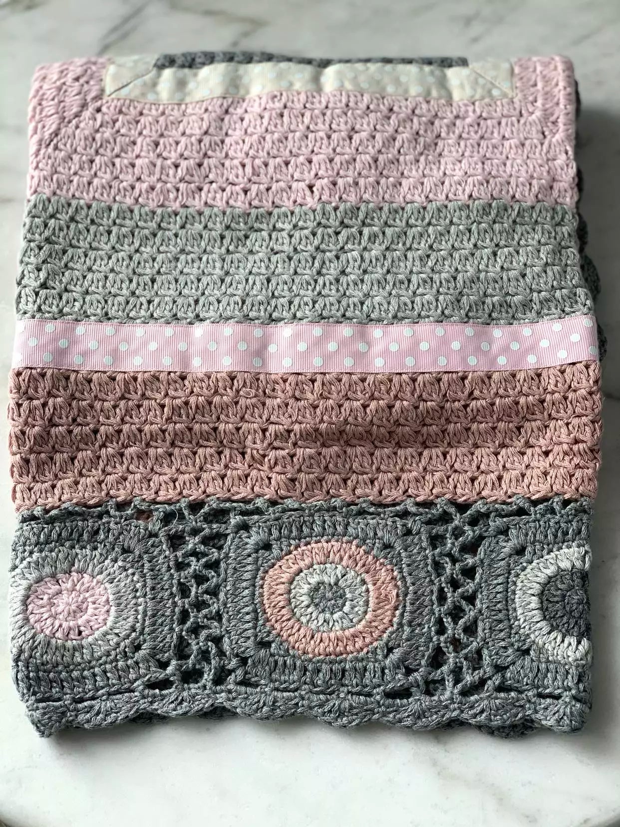 A Hand Crochet Blanket - Dusty Pink / Beige / Grey by and the little dog laughed on a marble table.