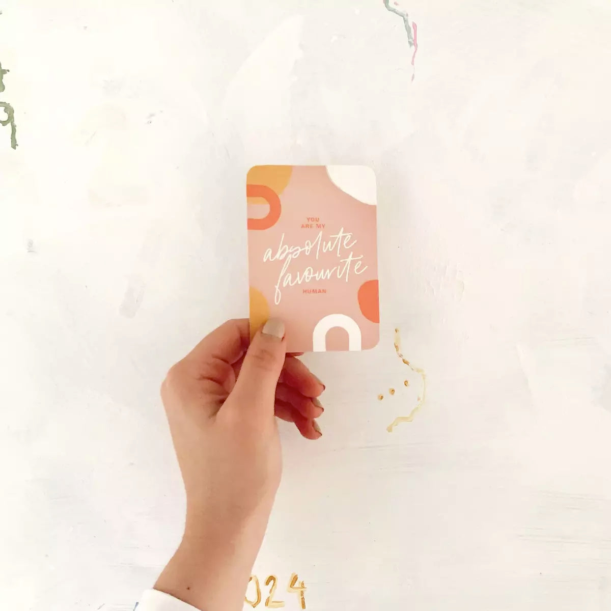 A person holding up a Kindness Card from Collective Hub, with the words "happy little mama", aiming to brighten someone's day and bring an unexpected smile.