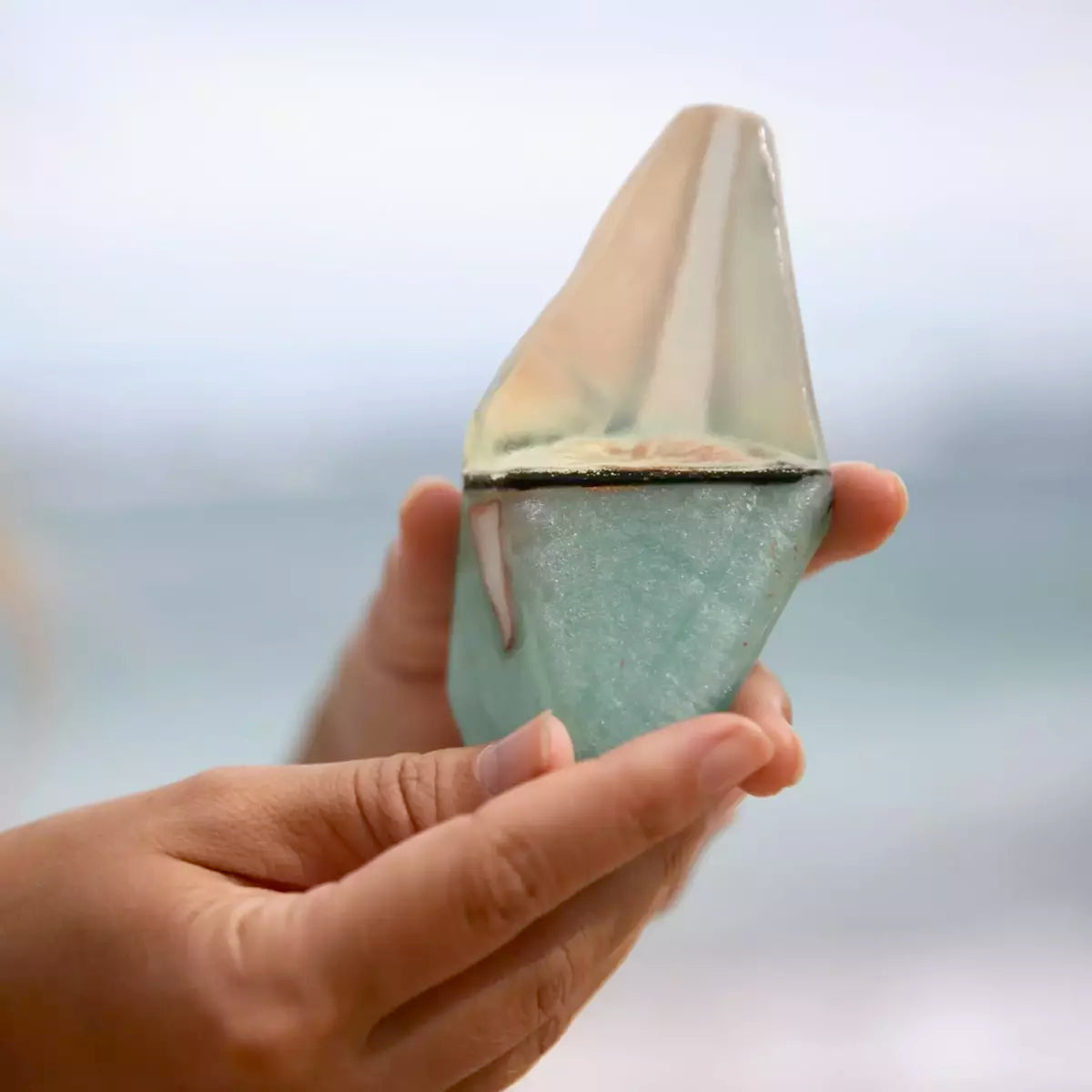 A person holding a small Summer Salt Body Crystal Soap - AQUAMARINE - Lemongrass on the beach.