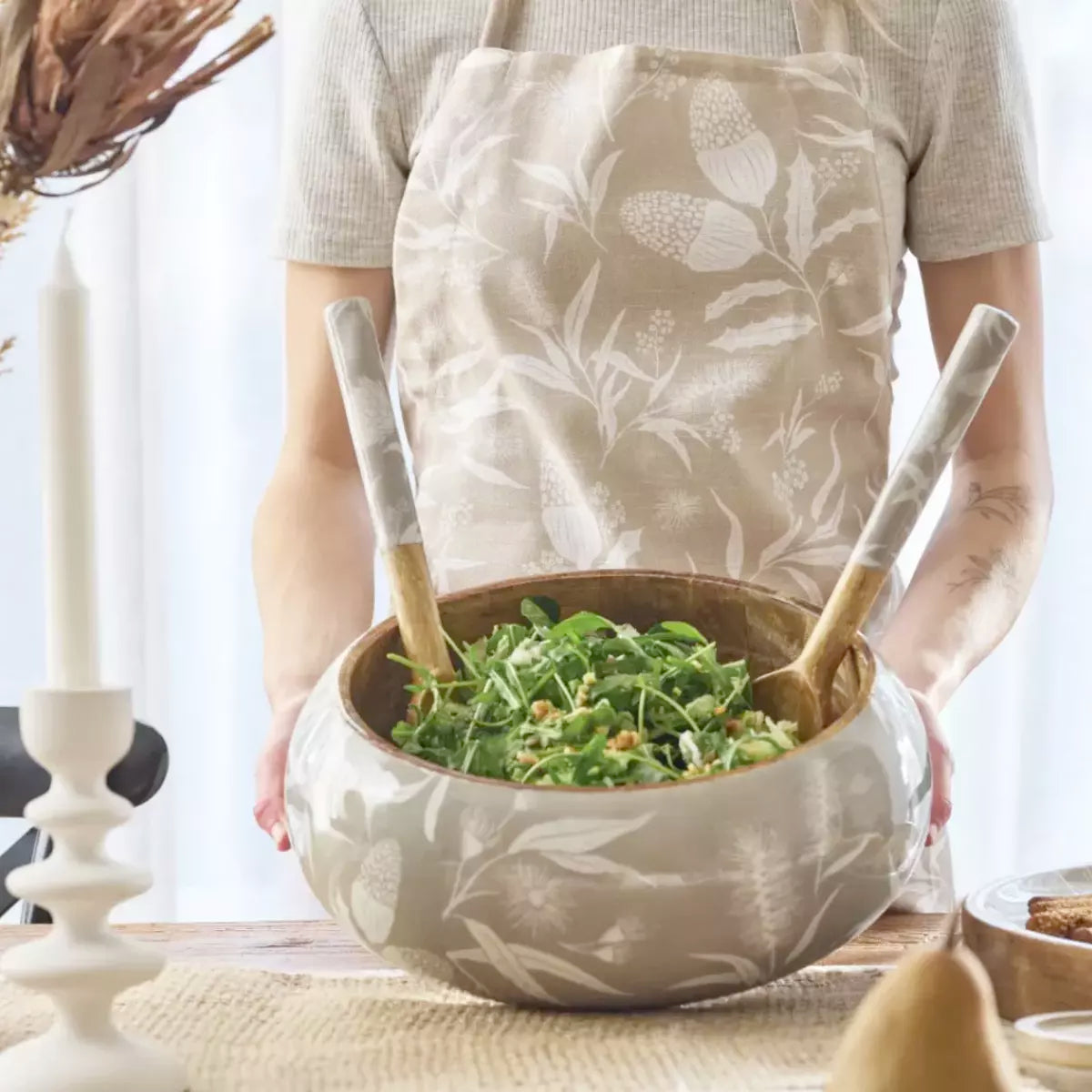 A woman in an apron holding a Bindi Salad Bowl inspired by Australia's native flora, from the j.elliot brand.