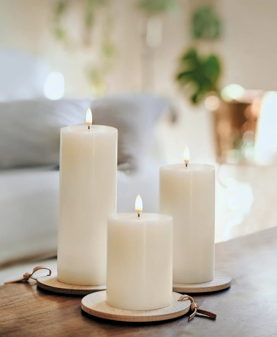 Three Enjoy Living Nordic White Flameless Pillar Candles on a wooden table.
