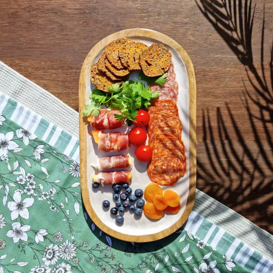 A j.elliot Como Oval Serving Tray made of mango wood, showcasing an embossed pearl design. This elegant tray is perfect for serving a delightful combination of meat, fruit, and vegetables.