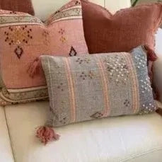 A white couch with pink Mya Mini Cushion pillows and tassels from L&M Home.
