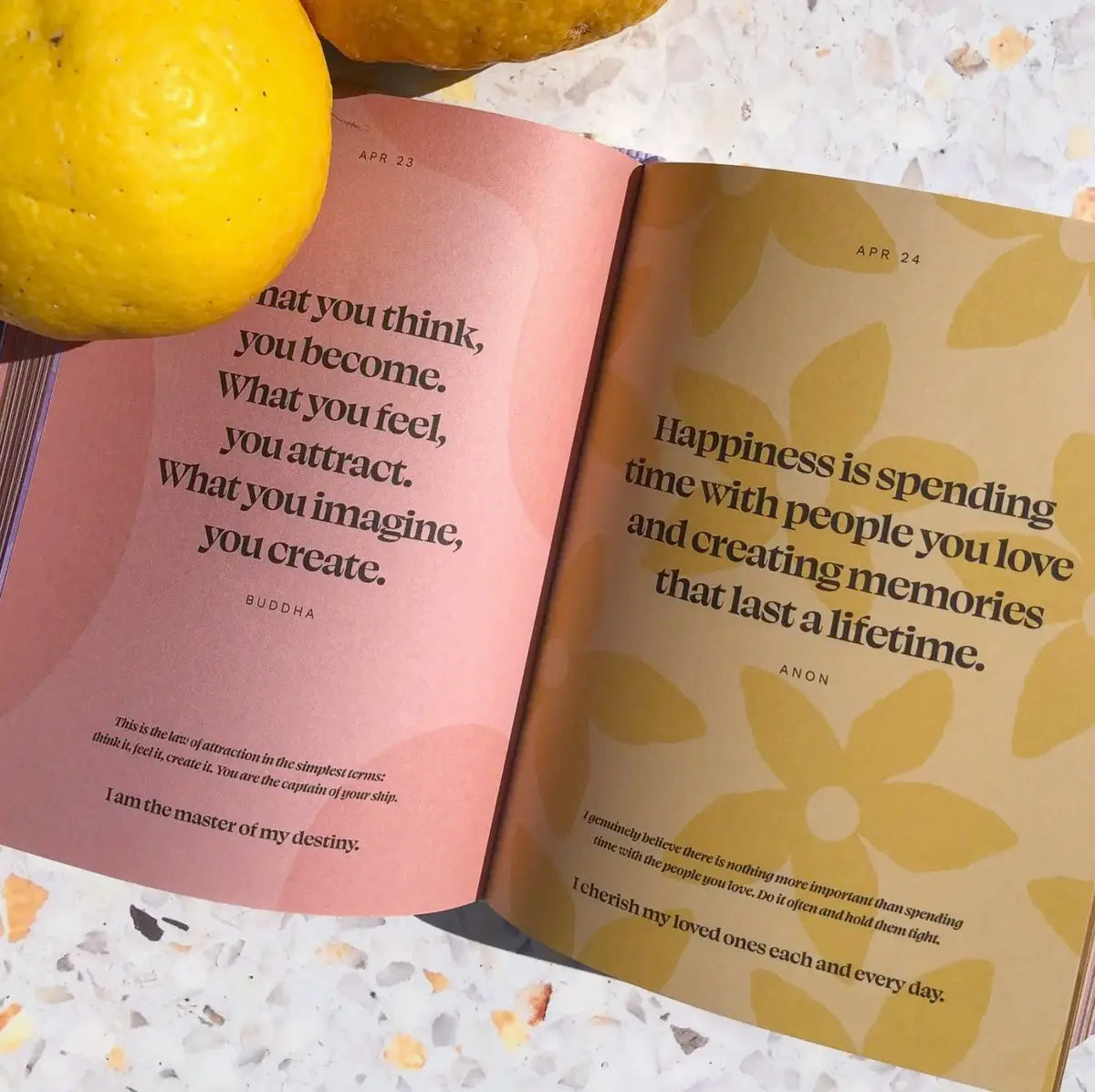 A curated book of quotes, Daily Mantras to Ignite Your Purpose - V3 by Collective Hub, with lemons next to it, providing inspiration.