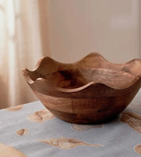Thumbnail for The Hazel Wavy Bowl by Madras Link, handcrafted from mango wood, rests on a light blue tablecloth with seashell accents—an ideal touch for contemporary dining spaces.