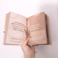 Thumbnail for A person holding an open book with a quote on it, providing affirmations for Daily Mantras to Ignite Your Purpose Second Edition by Collective Hub.