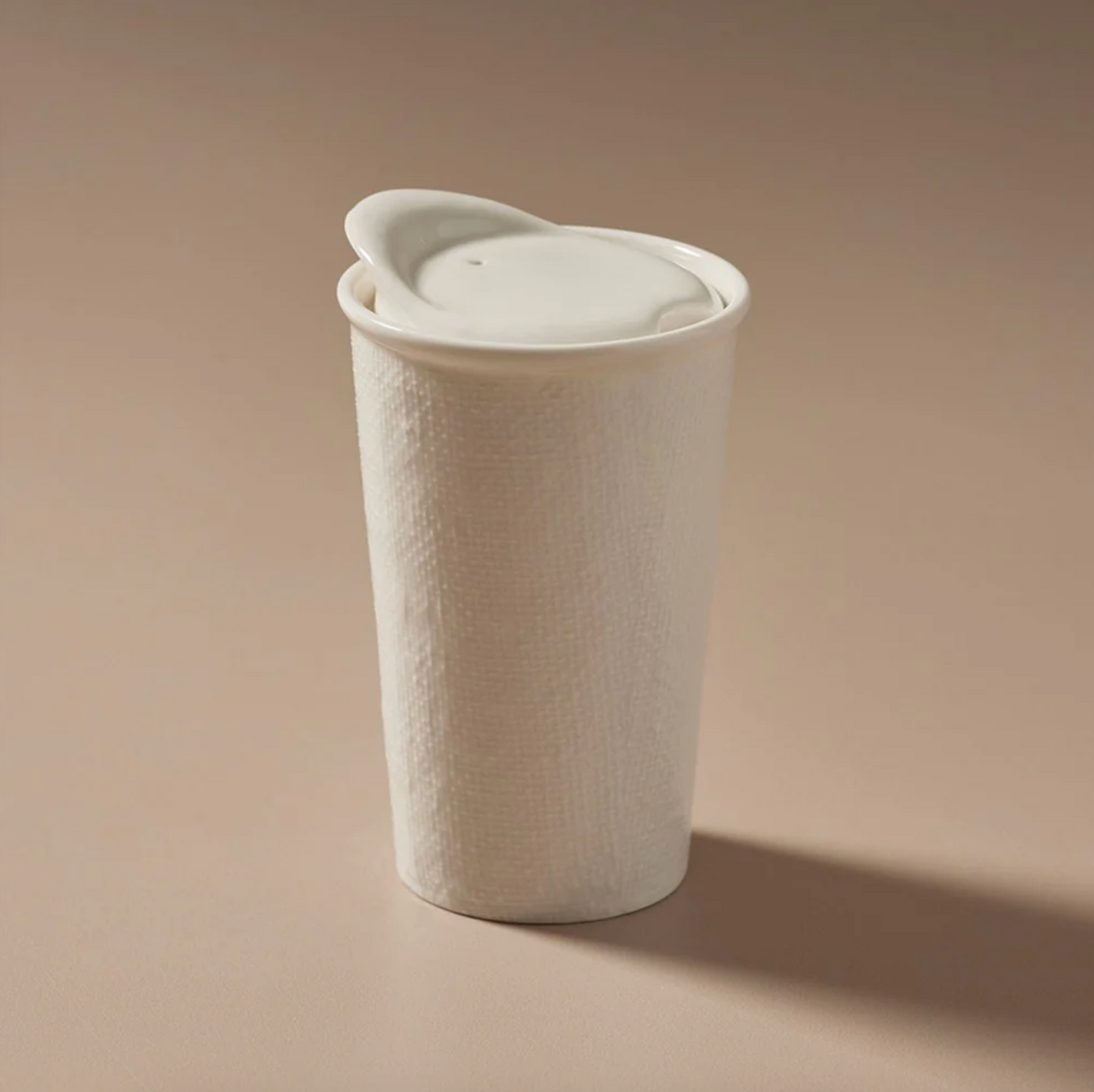 An Indigo Love Keeper Cup - Ceramic - White Linen with a sealable lid sitting on a table.