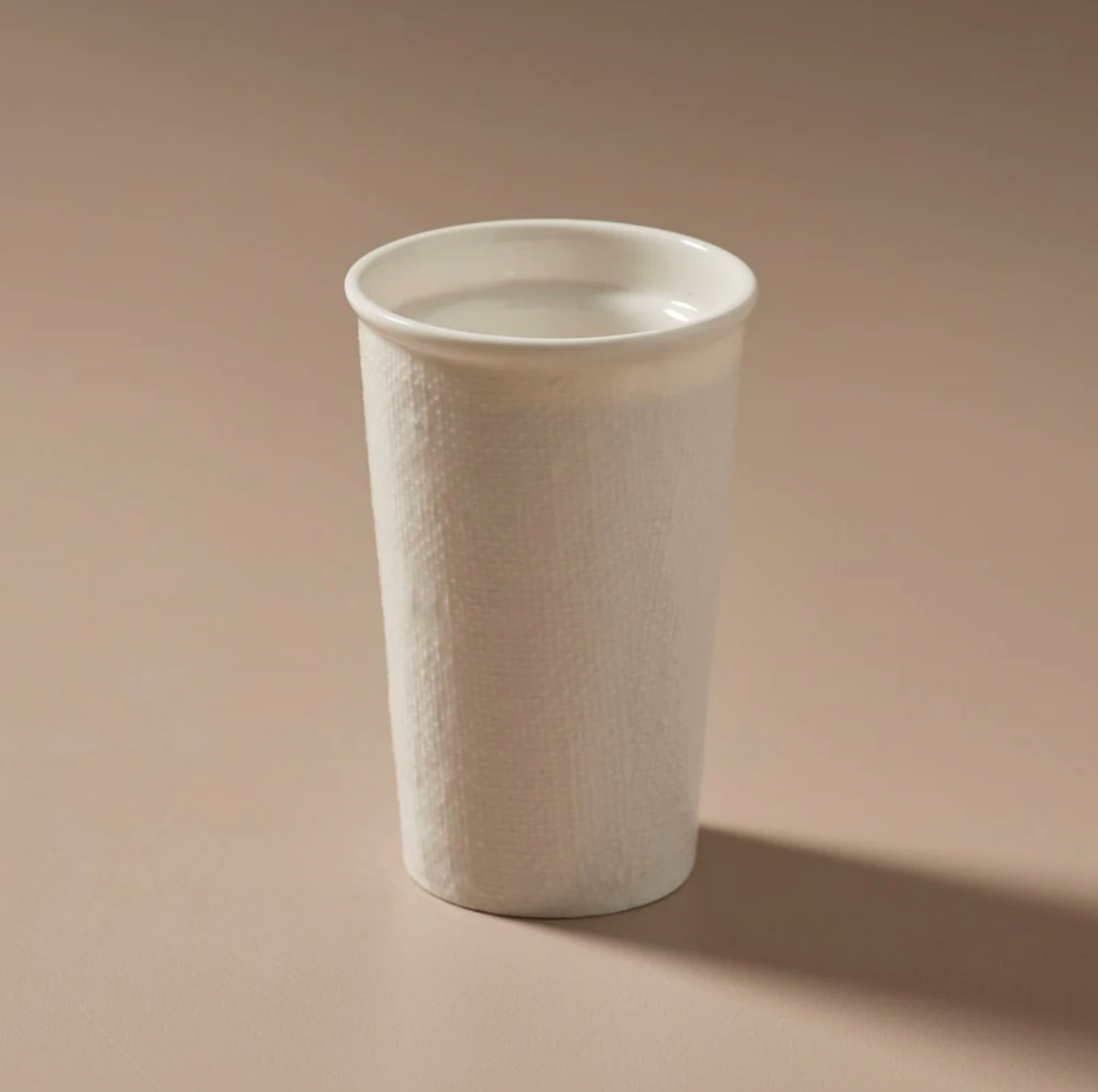 An Indigo Love Keeper Cup - Ceramic - White Linen sitting on a beige surface, featuring a sealable lid.