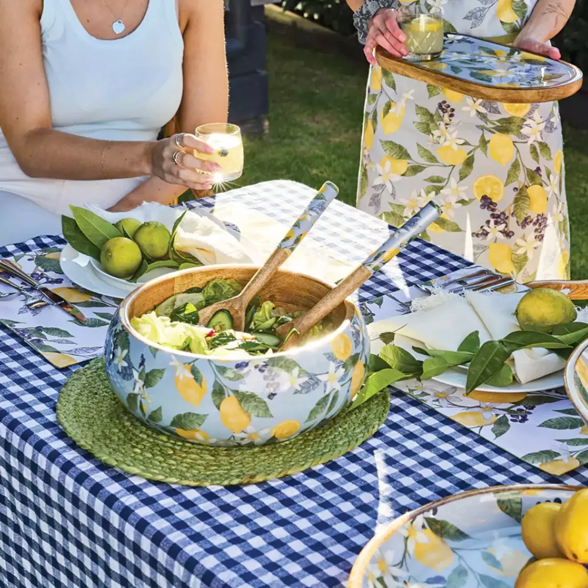Two women are sitting at a table with j.elliot's Lemon Round Serving Tray and lemons.