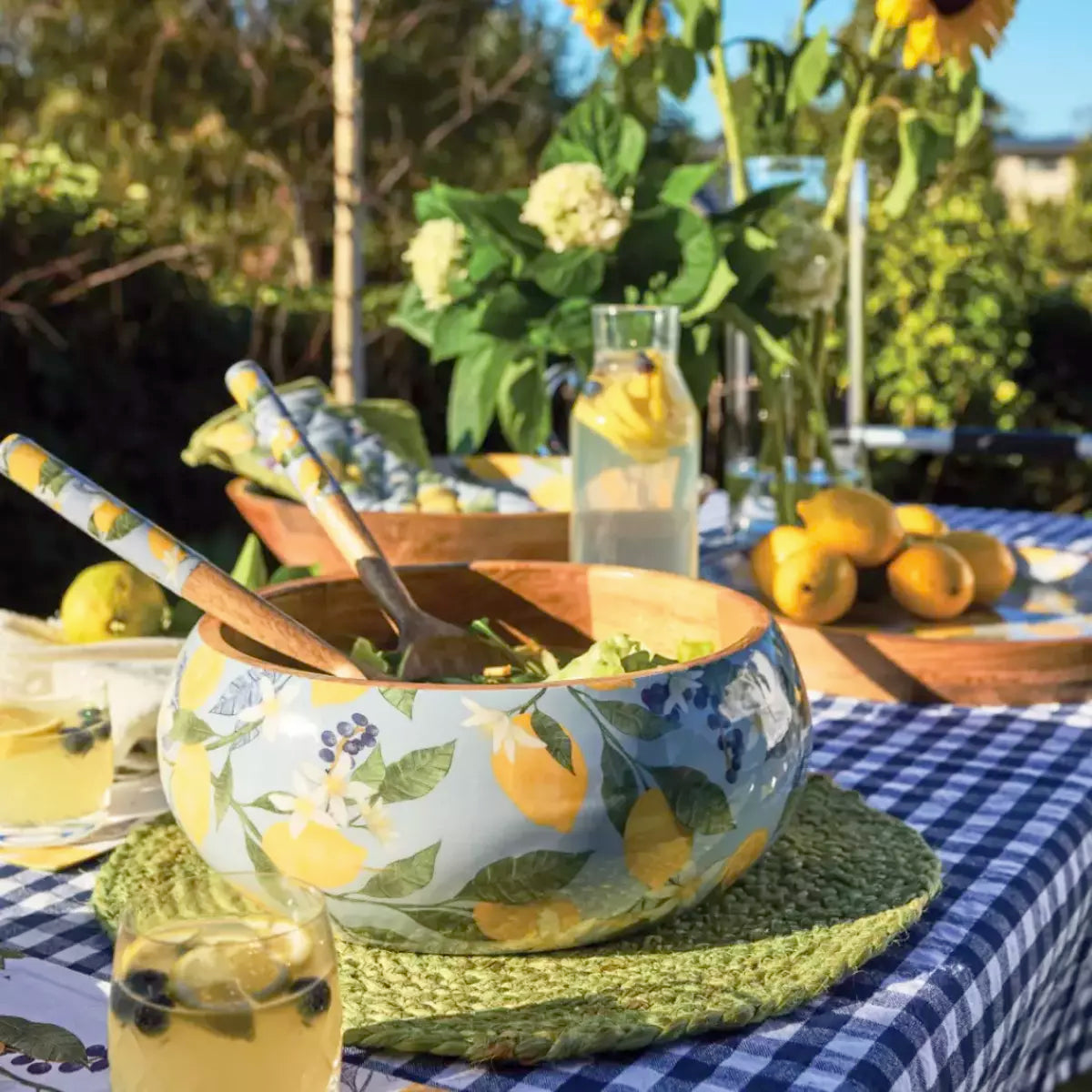 A table setting with lemons and sunflowers on a checkered tablecloth featuring a Lemon Salad Bowl in mango wood, by j.elliot.