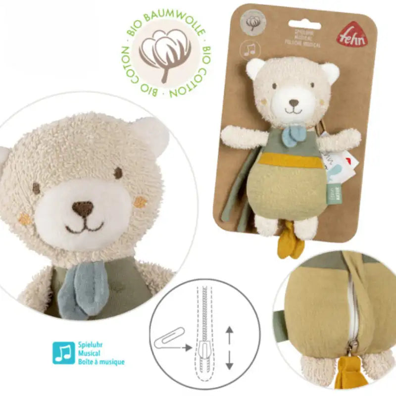 The Pilbeam FehnNATUR Mini Musical Bear, made of organic cotton in beige and green with a blue scarf, is a plush sleeping aid. Close-up and full-view images show its music box icons, packaging, and zipper detail.