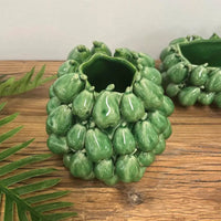 Thumbnail for The Mode Pear Vase by Mediterranean Markets, a green ceramic piece inspired by classic Sicilian vases, rests on a wooden surface near a fern leaf, with another similar vase visible in the background.