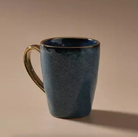 Thumbnail for An Indigo Love Senseo Mug - Deep Blue with a gold handle on a beige background.