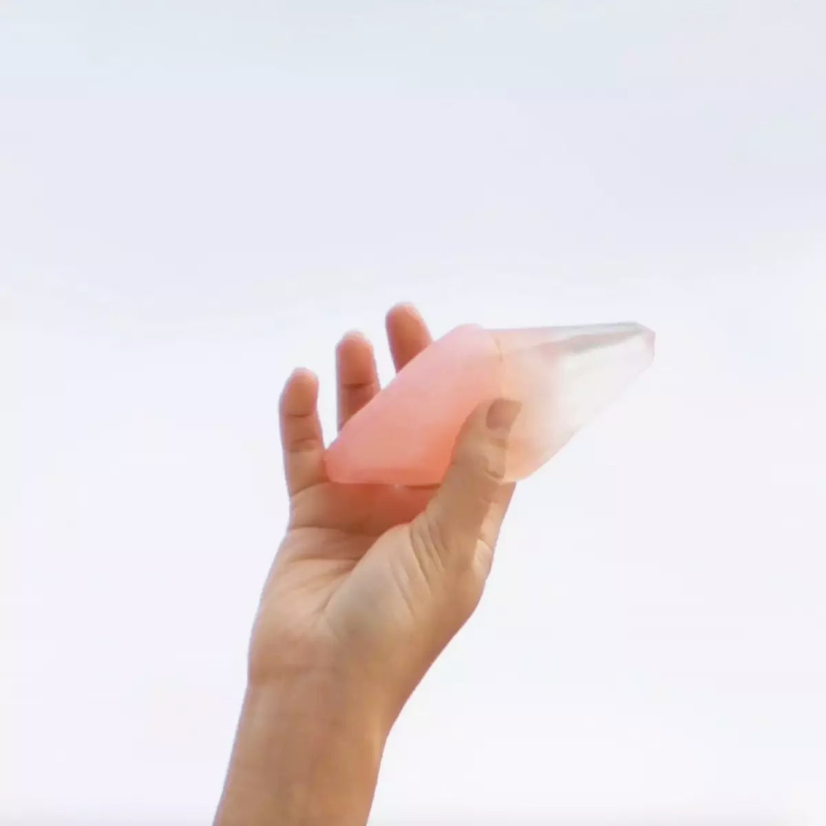 A person's hand holding up a Summer Salt Body Crystal Soap - ROSE QUARTZ - Jasmine, radiating self-love.
